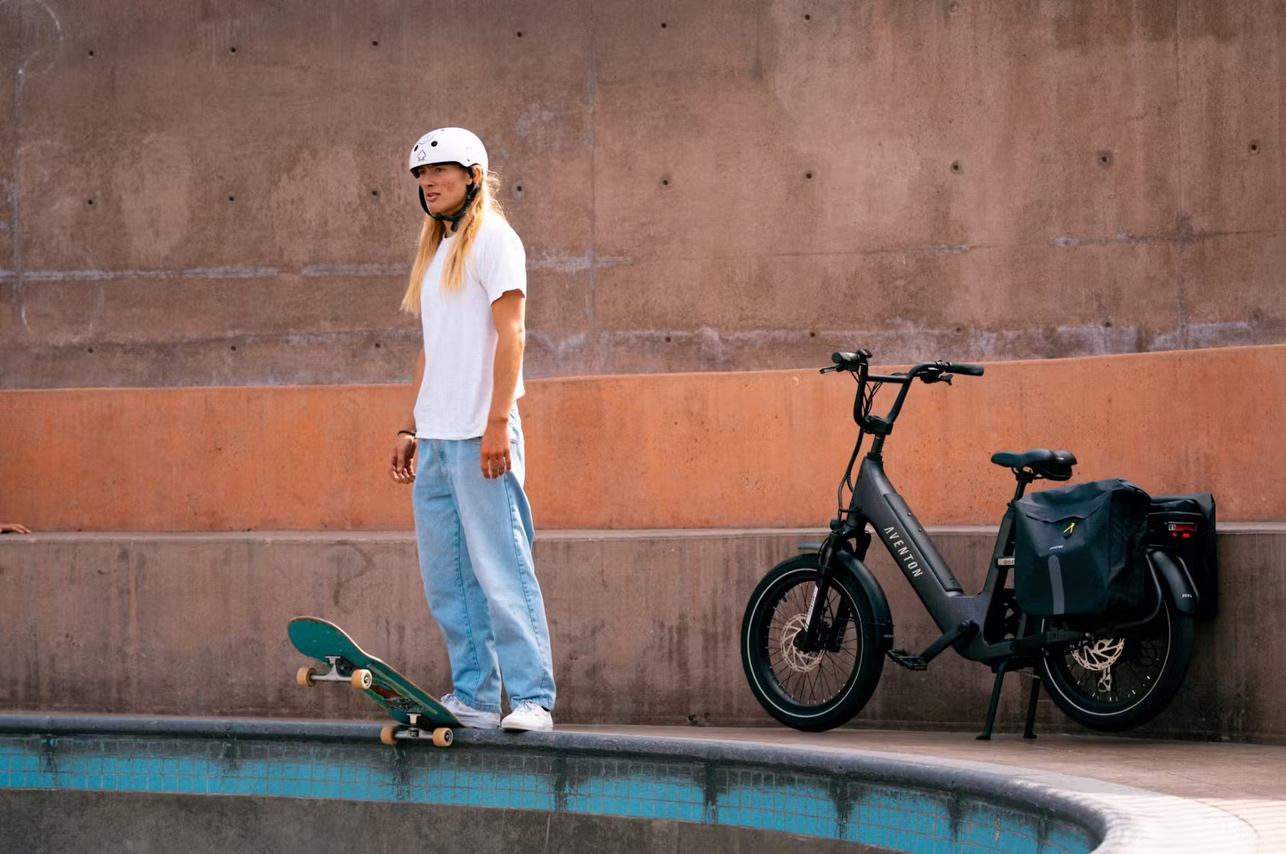 Rex E-Bikes Aventon Abound SR cargo e-bike parked next to a skateboarder wearing a white helmet and casual clothes