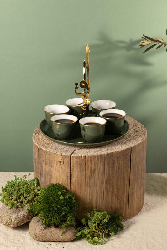 Arabic coffee cups set with holder in green and gold on a wooden display with greenery accents