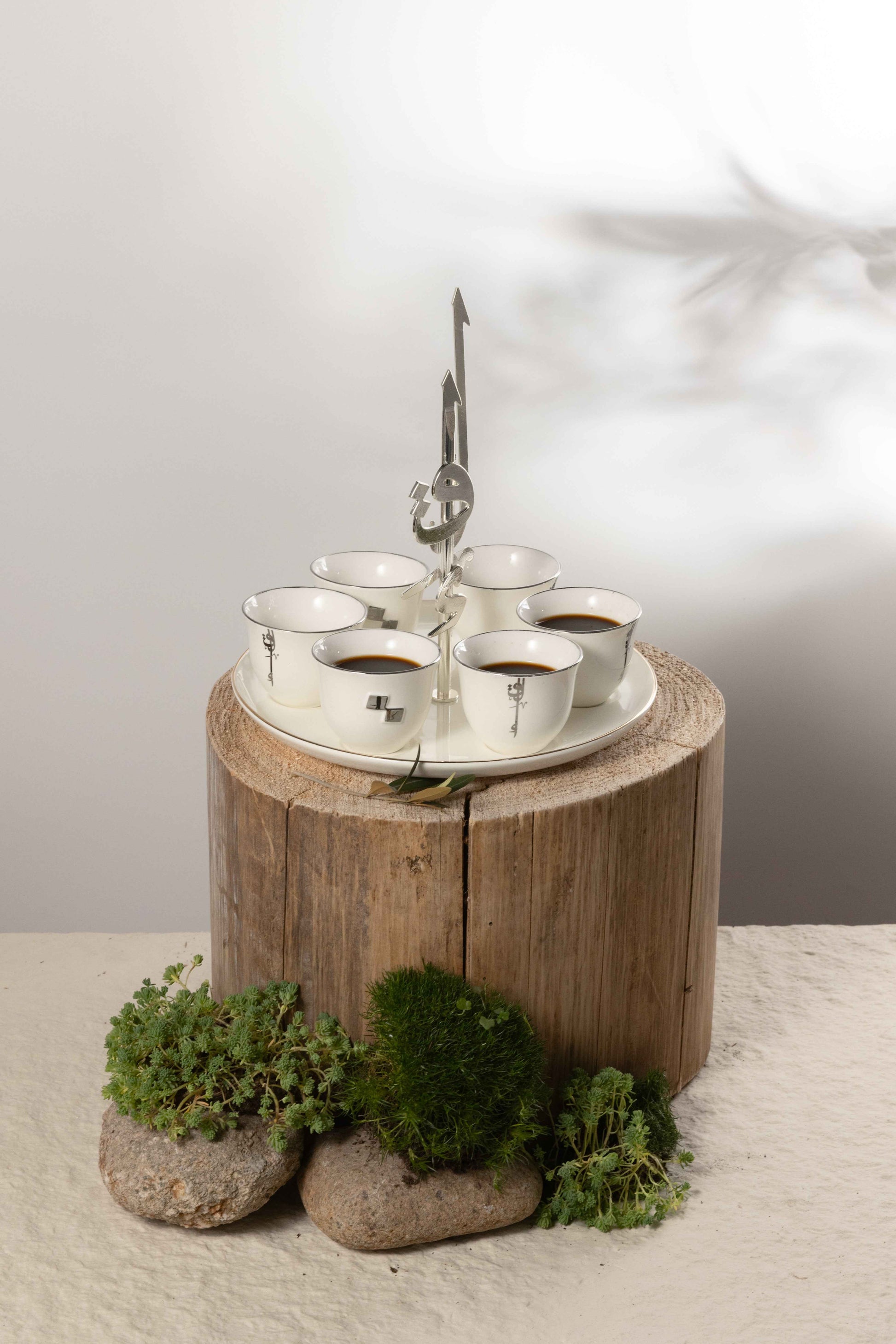 Arabic coffee cups set with holder featuring white cups and metal stand on rustic wooden surface