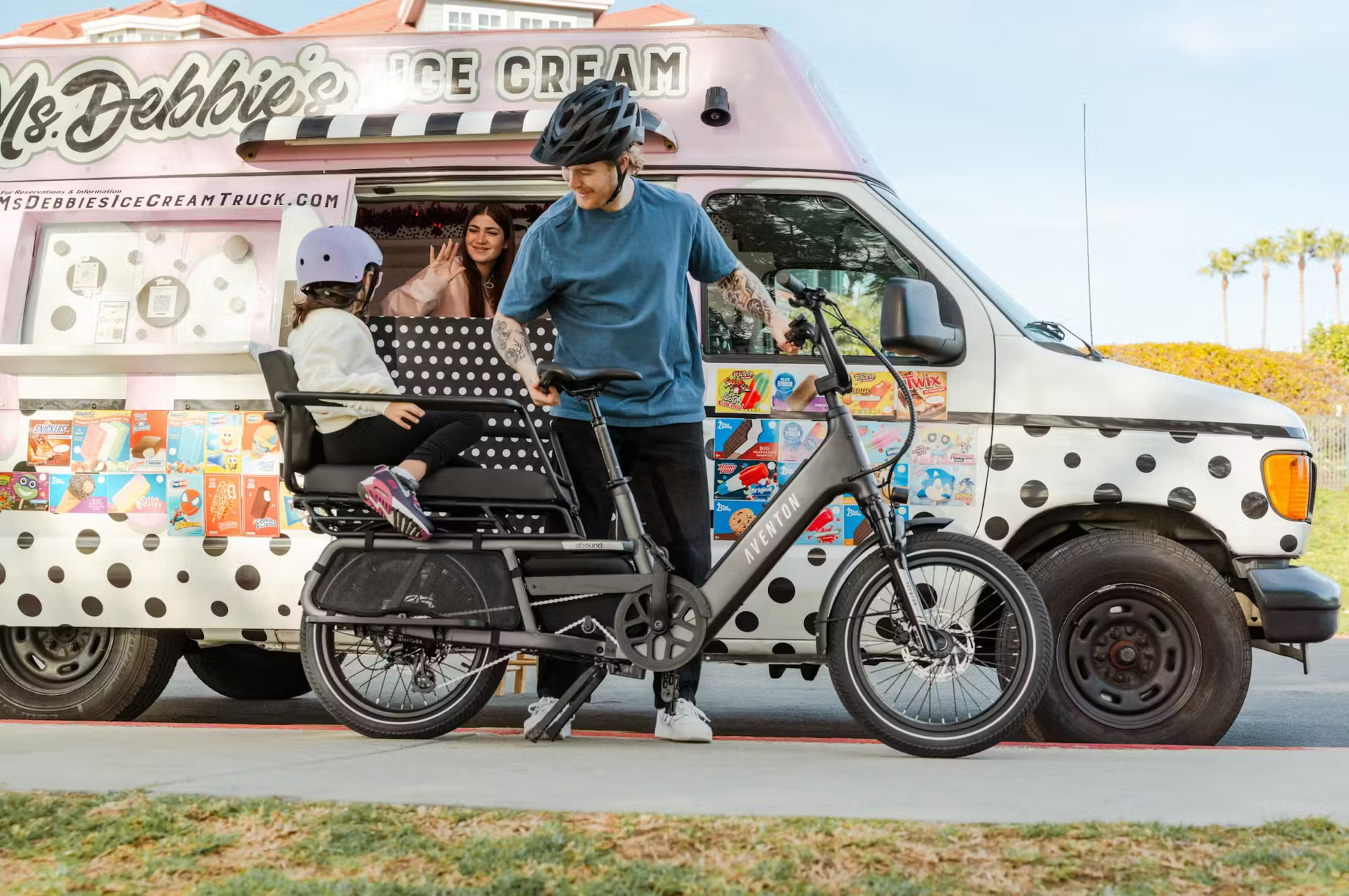 Rex E-Bikes Aventon Abound LR cargo e-bike with child seat parked by ice cream truck with rider and child