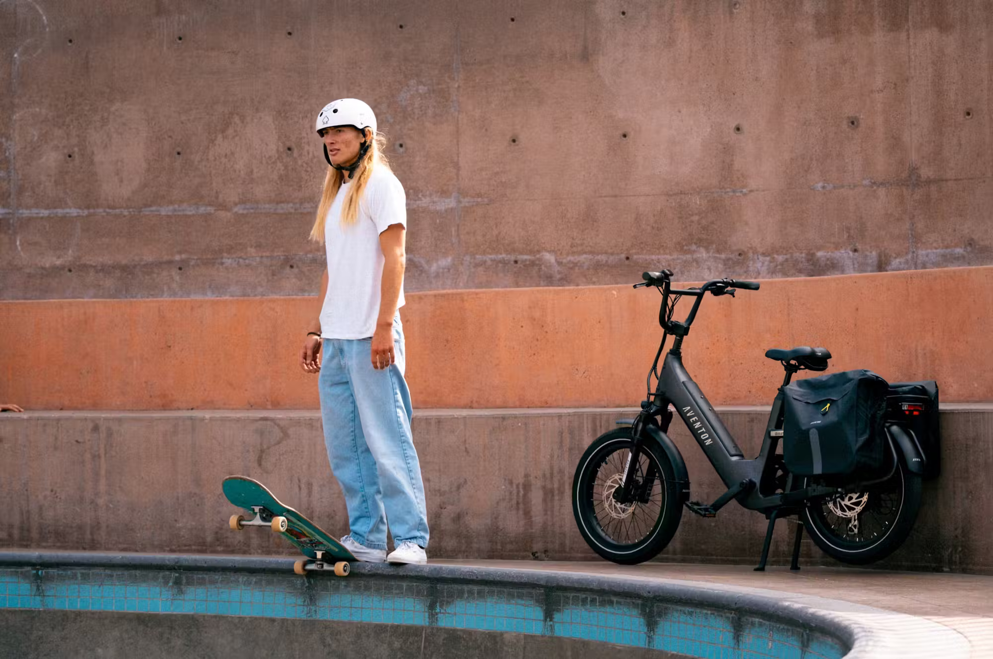 Rex E-Bikes Aventon Abound SR cargo e-bike parked next to a skateboarder wearing a white helmet and casual clothes