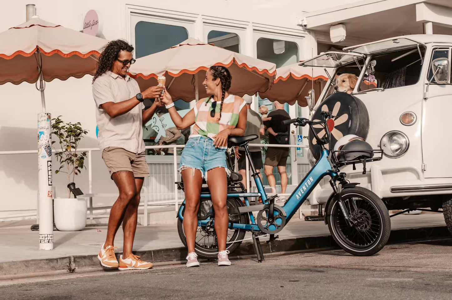 Aventon Abound SR cargo e-bike in blue parked on sidewalk with man and woman exchanging keys nearby