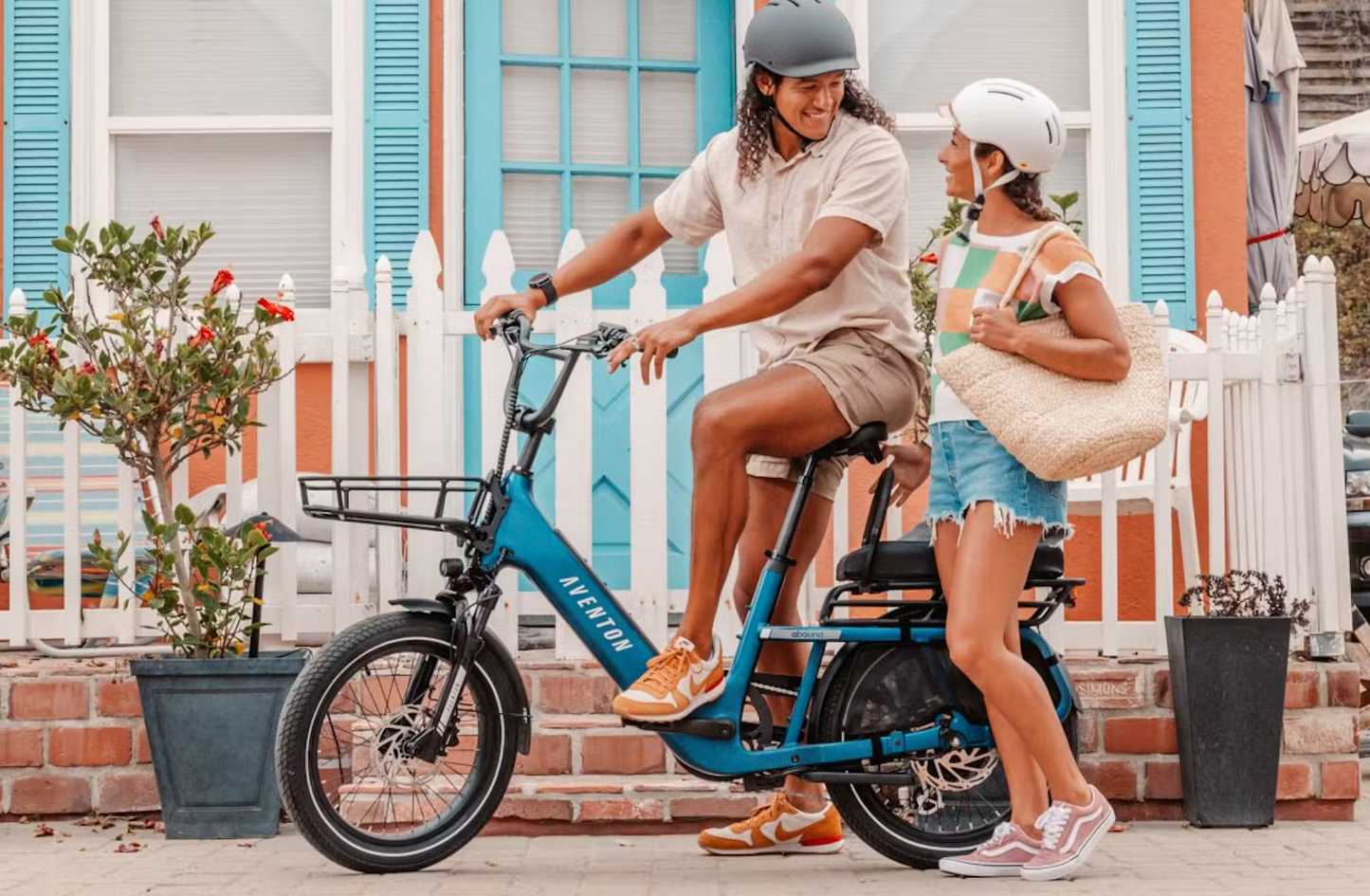 Aventon Abound SR cargo e-bike in blue with man riding and woman standing next to bike in urban setting