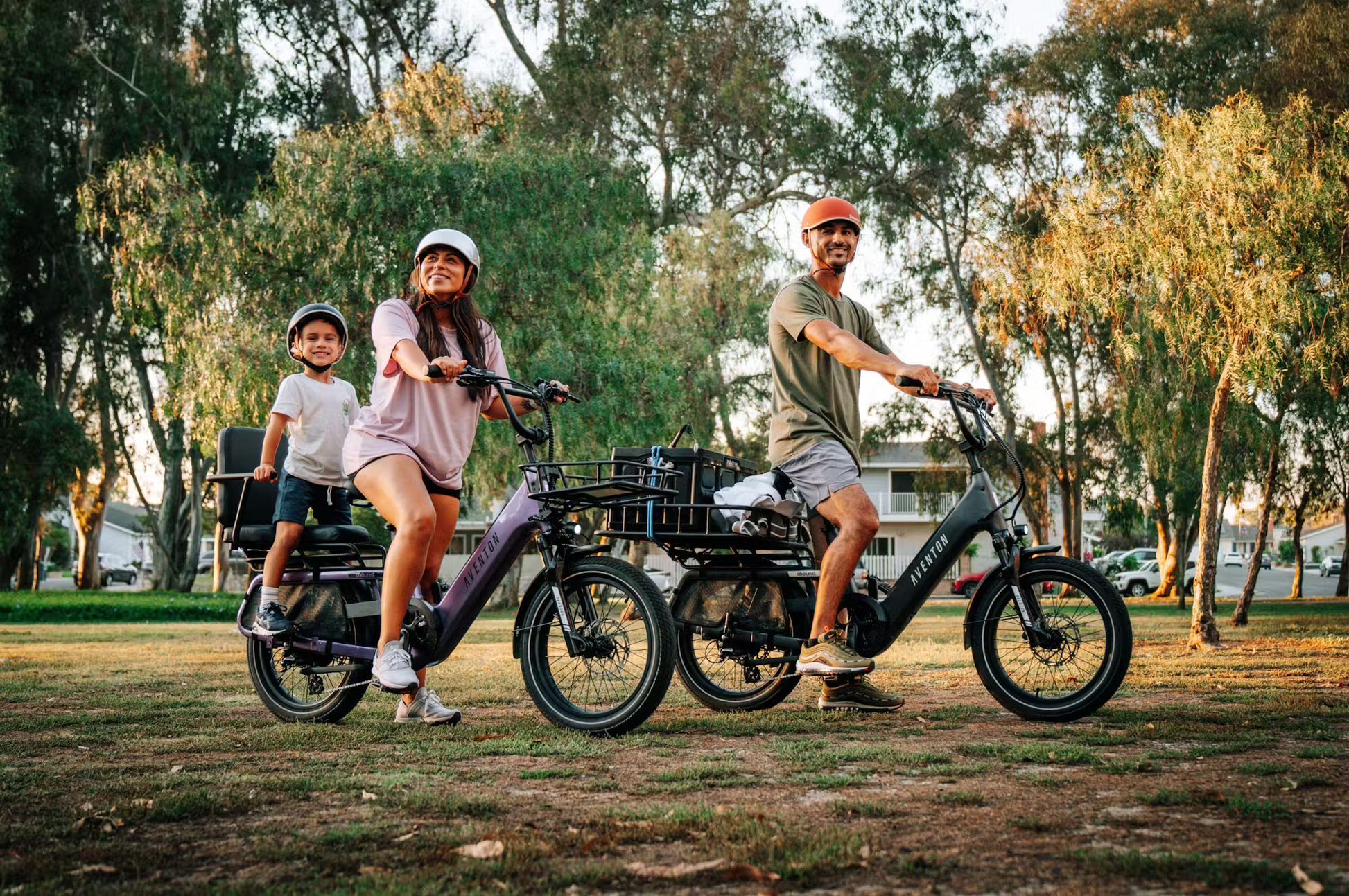 Family riding Aventon Abound SR cargo e-bike in park with child passenger and cargo basket