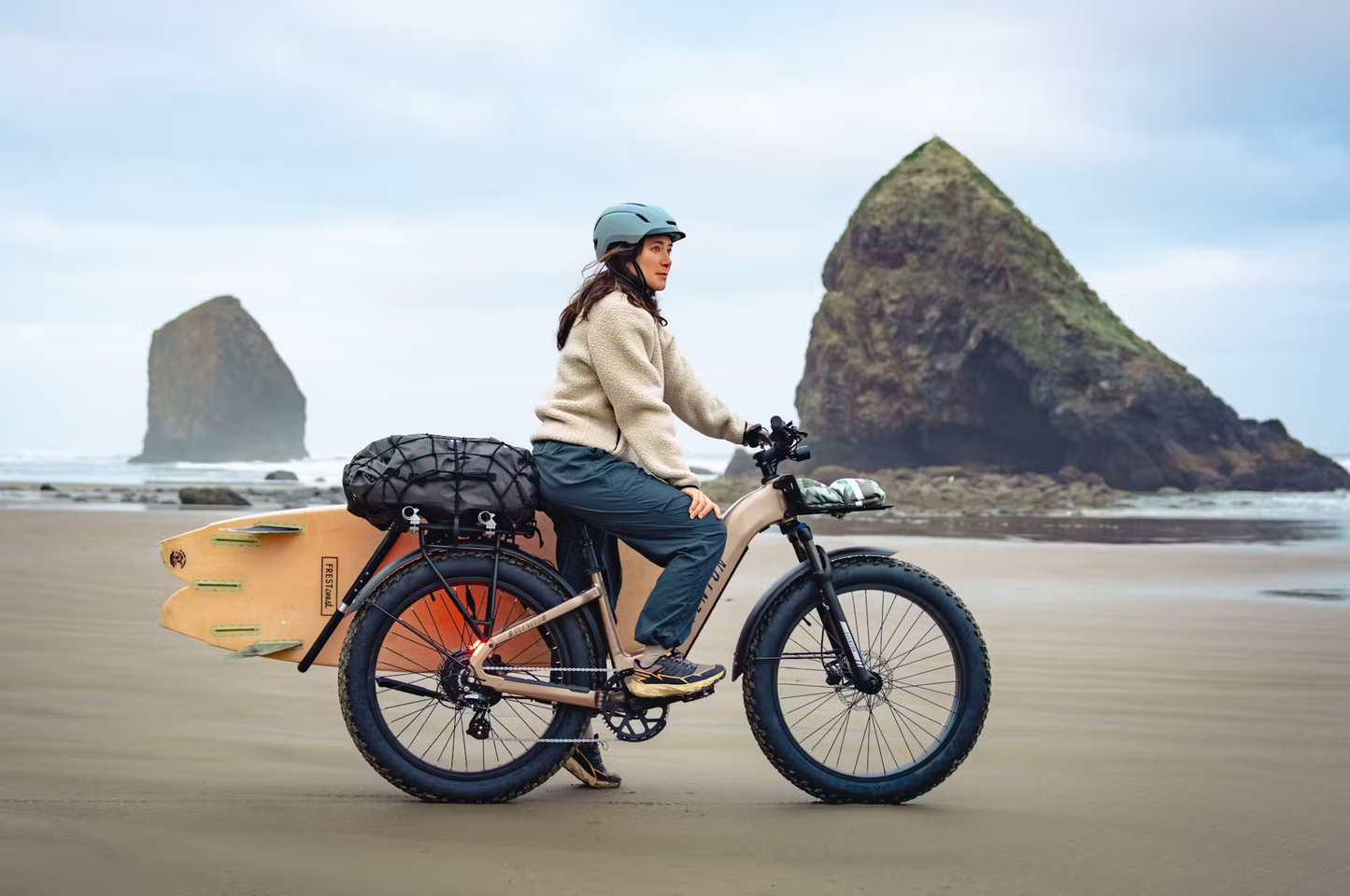 Rex E-Bikes Aventon Aventure.3 step-through e-bike on beach with surfboard and gear loaded on rear rack