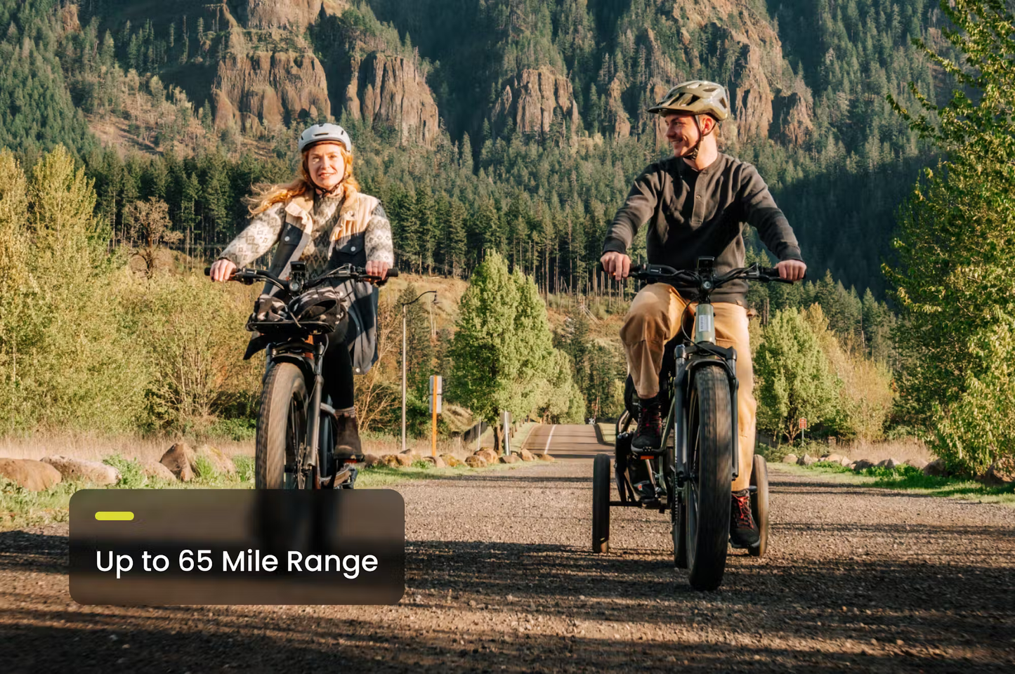 Couple riding Aventon Aventure.3 e-bike for sale on forest trail with up to 65 mile range