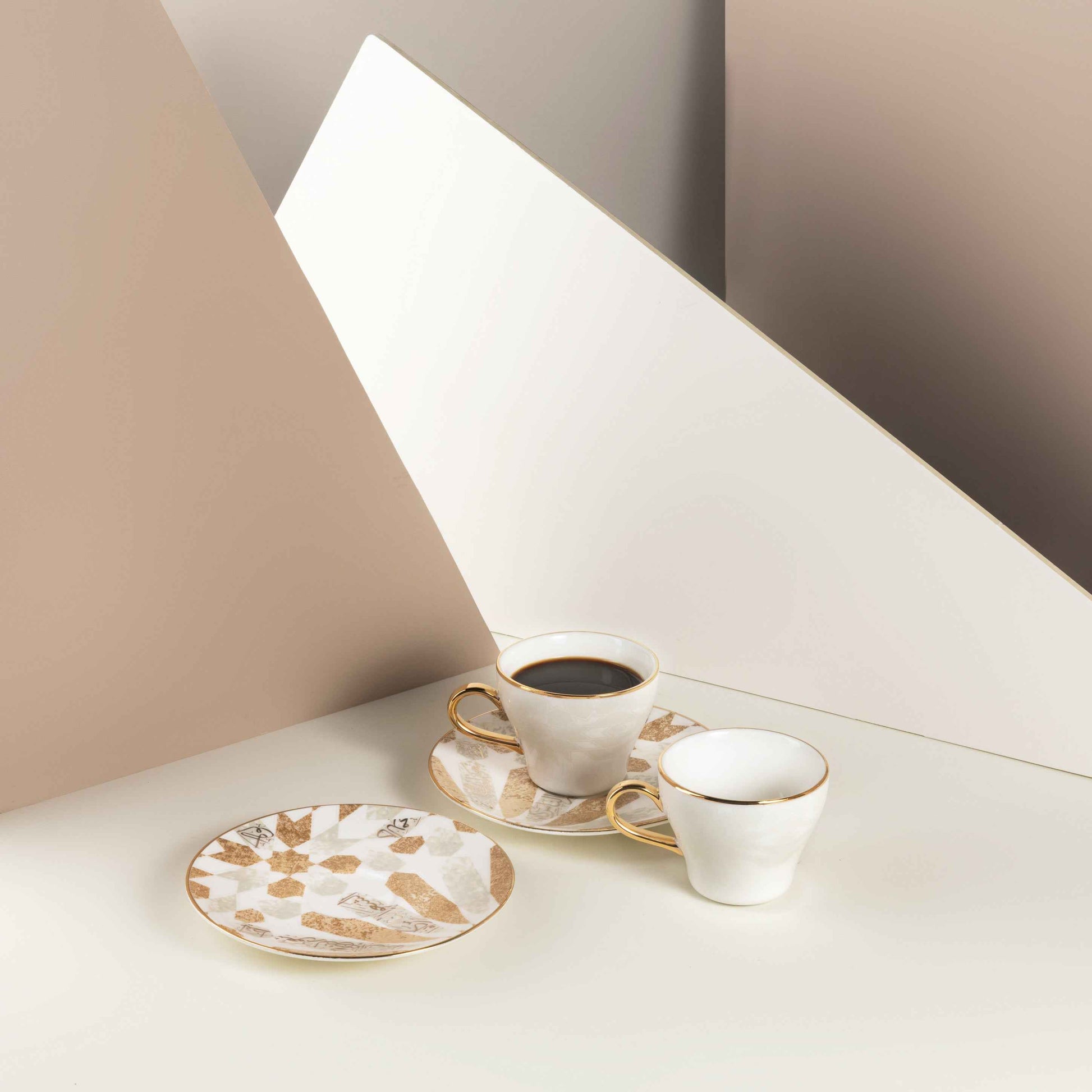 Beige and gold espresso cups set with matching saucers displayed on a cream surface