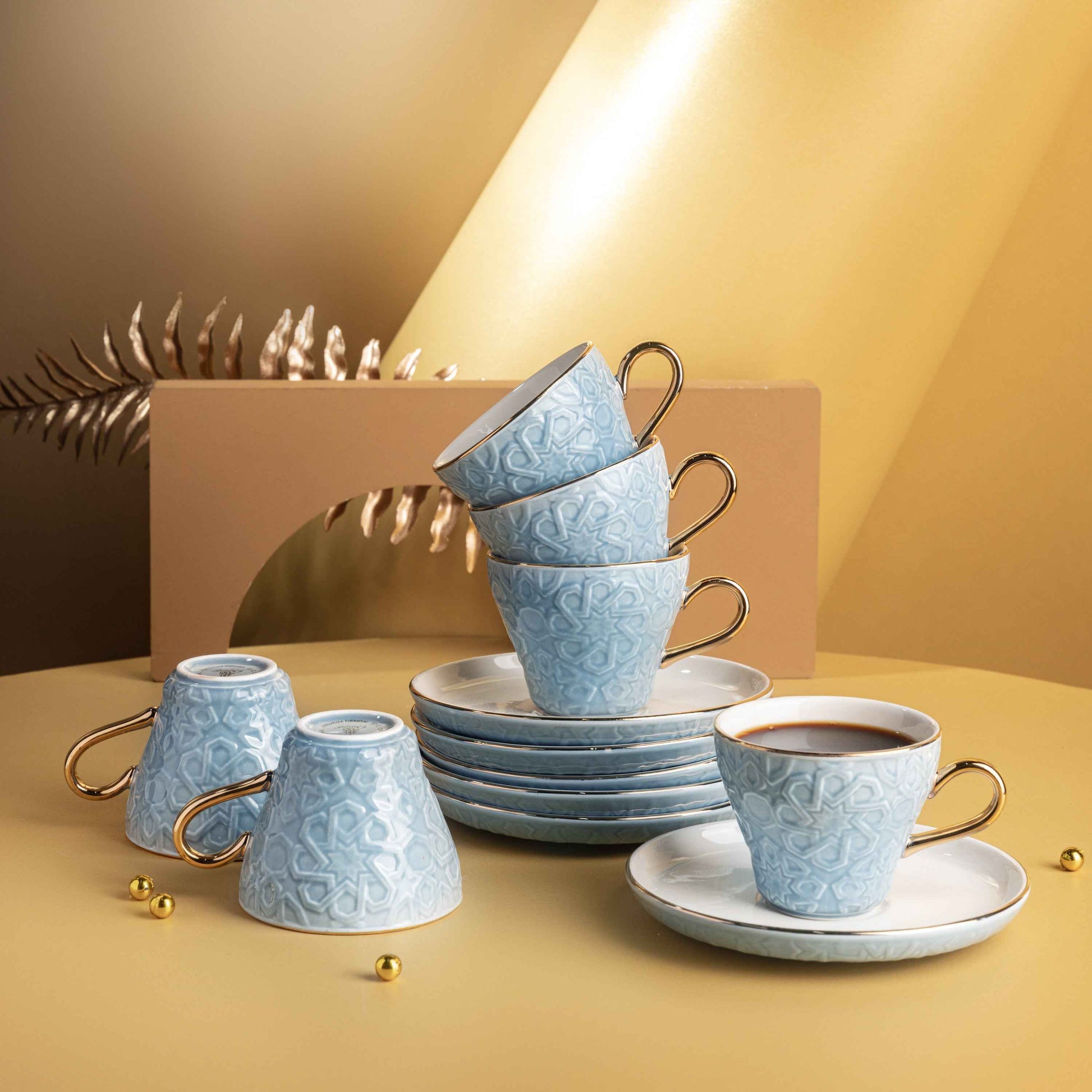 Baby blue Turkish coffee cups set with intricate patterns and gold handles stacked on plates