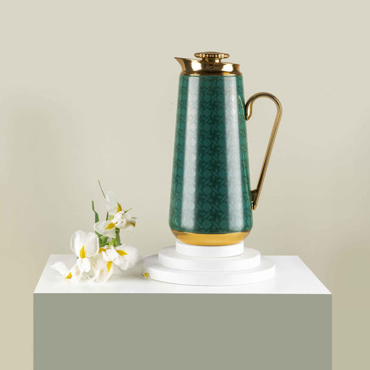 Green and gold vacuum flask with intricate pattern and elegant handle displayed on white pedestal with white flowers