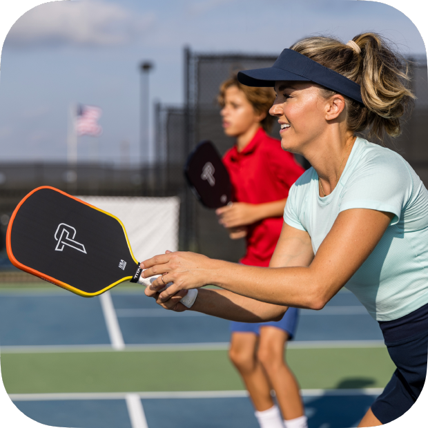 Woman playing pickleball holding Titan Ignite 16L pickleball paddle on outdoor court
