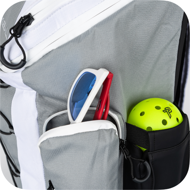 Close-up of gray and white Titan Pickleball Backpack pocket holding sunglasses and a neon yellow pickleball