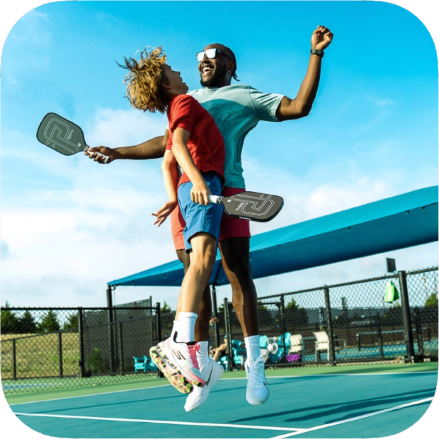 Two players jumping and celebrating on a pickleball court with Titan Pro Titanium pickleball paddle in hand