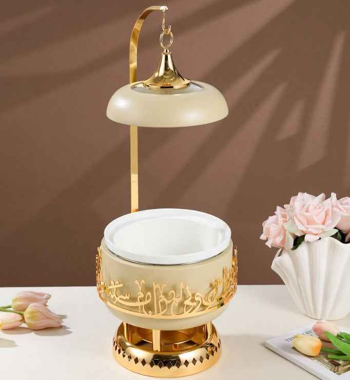 Ivory and gold chafer with decorative golden accents and a hanging lid for serving food